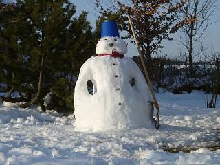 Dicker Schneemann mit Eimer als Hut und roter Schleife
